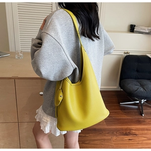 Detail view of mustard yellow lychee texture leather bucket bag with leaf pendant charm