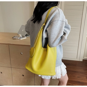 Detail of yellow litchi leather bucket bag showing large capacity and round charm