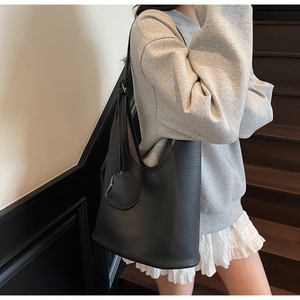 Detail of black lychee grain leather bucket bag with a small matching round charm pouch