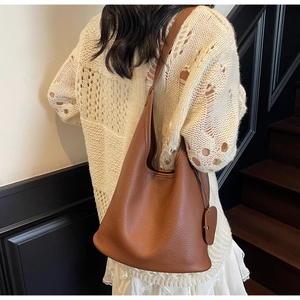Detail of caramel brown litchi pattern bucket bag with heart charm and wide strap