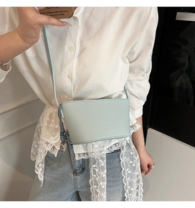 Detail van een lichtblauwe emmer tas van leer met lychee textuur en metalen hanger