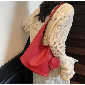 Detail of red lychee grain leather bucket bag with matching round charm pendant
