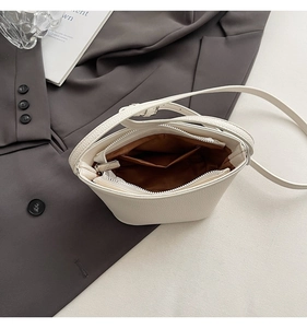 Detailopname van witte bucket bag interieur met bruine voering en ritsvakje binnen