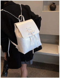 Rucksack aus weißem Kunstleder mit Kreuzschnürung und silbernen Kettenriemen im Detail