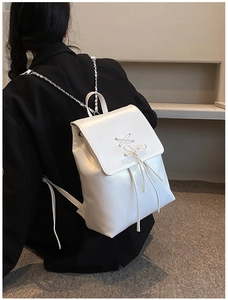 Detail eines weißen PU-Lederrucksacks mit Schnürschleife und silbernen Kettenriemen
