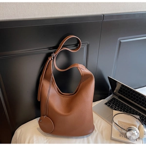 Detailed texture of brown litchi grain leather bucket bag with artistic props