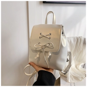 Detail eines weißen Perlmutt-Minirucksacks mit Schnürösen aus Metall und einer Schleife