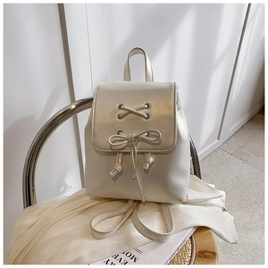 Detail eines cremeweißen Mini-Rucksacks mit schicker Schleife und glatten Metallösen