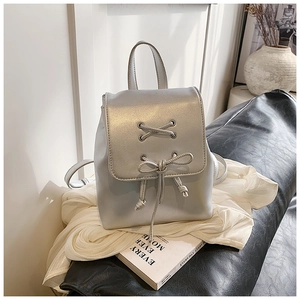 Detail eines silbernen metallischen Rucksacks mit Schleifendekor und Kordelzugverschluss