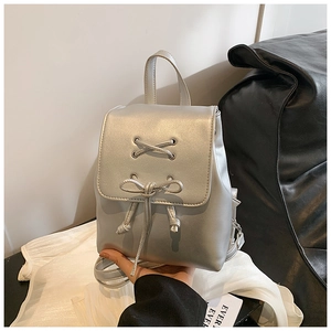 Detailansicht eines silbernen Metallic-Mini-Rucksacks mit Schleife und Schnürung am Deckel