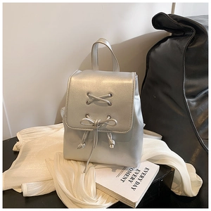 Detail eines silbernen Metallic-Rucksacks mit Schnür-Schleifen-Design auf Stoff
