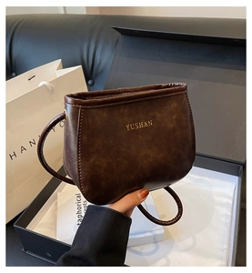 Dettaglio borsa in pelle marrone scuro con logo YUSHAN dorato e trama a grana