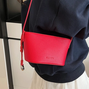 Chique rode emmer tas van leer met zilveren bolbedeltje gedragen door model