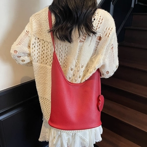 Red lychee pattern leather hobo bag with heart charm worn by model in casual setting