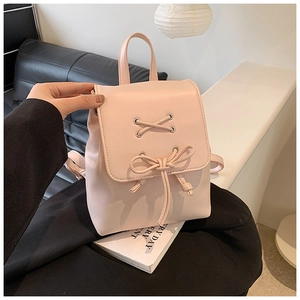 Nahaufnahme des rosa PU-Lederrucksacks mit silbernen Ösen und Schleife in der Hand gehalten