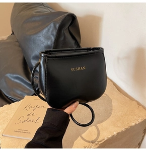 Dettaglio della borsa a tracolla a mezzaluna in pelle PU nera con logo dorato YUSHAN