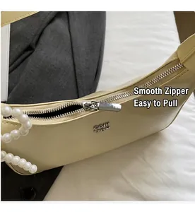 Detail of smooth silver zipper and pearl chain on light yellow leather underarm bag