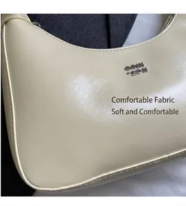 Close-up of cream white crescent underarm bag with silver logo and glossy leather finish