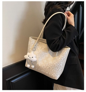 Detail of cream tote bag with geometric patterns, logo patch and cloud charm