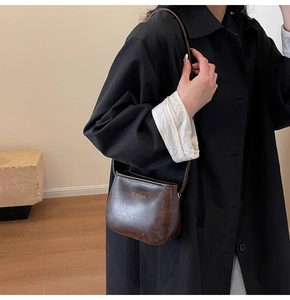 Dettaglio borsa a tracolla in pelle marrone scuro con logo YUSHAN dorato inciso