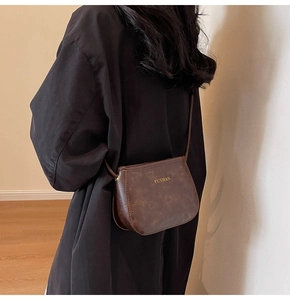 Dettaglio della borsa a tracolla vintage marrone scuro con scritta dorata impressa