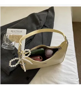 Detail view of cream underarm bag showing interior capacity with phone and pearl charm