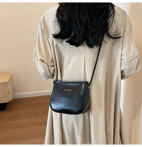 Borsa a tracolla in pelle PU nera indossata da una modella in cappotto beige