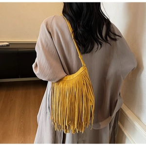 Close-up of yellow suede fringed crossbody bag with long tassels and bohemian design
