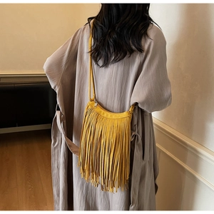 Close-up of yellow suede fringed shoulder bag with bohemian tassels and zipper detail