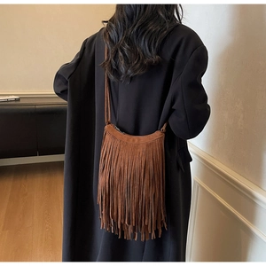 Brown faux suede crossbody bag with long tassels shown in a stylish lifestyle back view