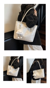 Detail of cream tote bag featuring geometric embossed patterns and a plush cloud charm