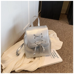 Detail eines silbernen Metallic-Minirucksacks mit Schleife und Schnürung-Design
