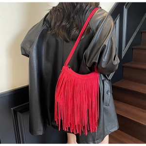 Close-up of vibrant red suede fringed crossbody bag with bohemian tassel detailing