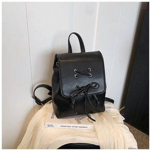 Detail eines schwarzen Kunstlederrucksacks mit Silberschnalle und Schleifendesign