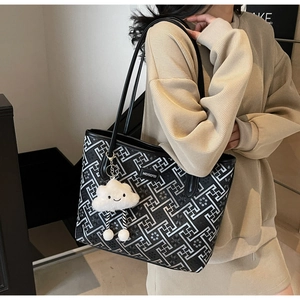 Detail of ethnic geometric tote bag with black straps and plush cloud charm accessory