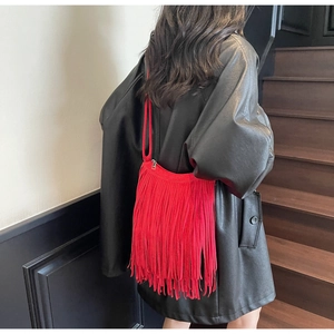 Rear view of red fringe shoulder bag with long tassels worn by model in black leather jacket
