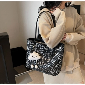 Detail of geometric pattern tote bag with white cloud charm on black shoulder strap