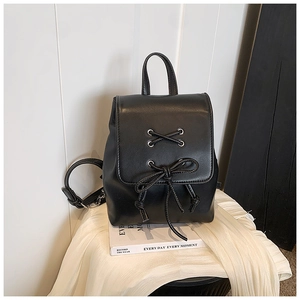 Detail eines minimalistischen schwarzen Rucksacks mit dekorativer Schleife und Metallösen