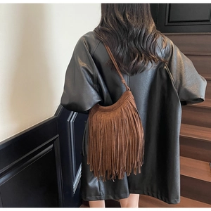 Detailed back view of a brown suede tassel hobo bag worn with a black leather jacket