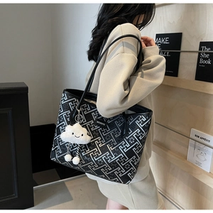 Close-up of black tote bag with silver geometric patterns and cloud plush pendant