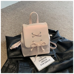Detail eines rosa Mini-Rucksacks mit Schnürschleife und Kordelzug auf schwarzer Lederjacke