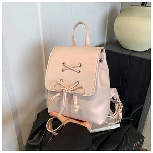 Detail eines blassrosa Mini-Rucksacks mit Kreuzschnürung und süßer Schleifenverzierung