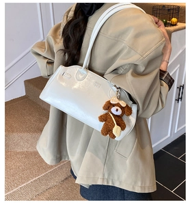 Detailed back view of model wearing white glossy shoulder bag with cute brown bear charm