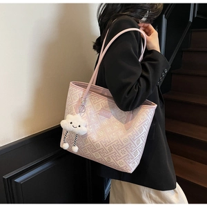 Detail view of pink tote bag with geometric patterns and white cloud plush pendant