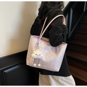 Detail of light pink tote bag with Greek key patterns and white cloud plush charm decoration