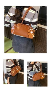 Detail of caramel oil wax leather handbag featuring a plush bear charm and embossed logo