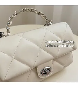 Vue détaillée d'un sac matelassé crème avec poignée argentée ondulée et fermoir rotatif