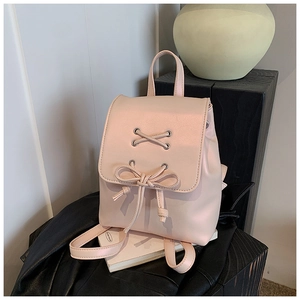 Detail eines hellrosa Mini-Rucksacks mit Schnürösen und einer dekorativen Schleife