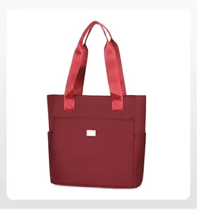 Detail of red water-resistant nylon tote bag with reinforced handles and metal logo