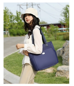 Detail of dark blue nylon tote bag with silver metal tag and durable grey woven handle